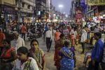 Pedestrians and shoppers walk past stores on a street in Varanasi, Uttar Pradesh, India.