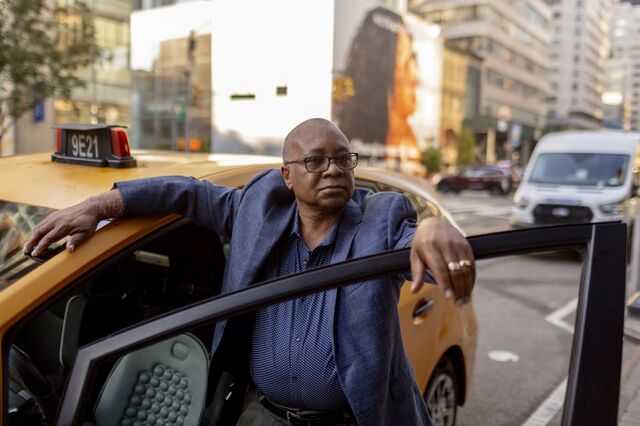 A portrait of Naider Henry outside his taxi cab. 