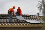 Workers install solar panels on a roof for Arizona Public Service Co. in Goodyear, Arizona.