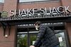 A pedestrian wearing a protective mask walks past a Shake Shack restaurant in Washington, D.C., U.S.