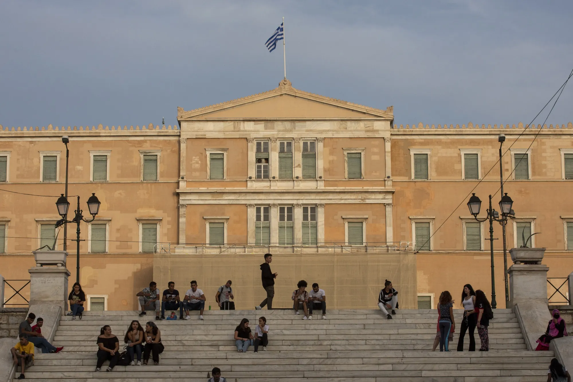 People sit on the steps in front of the parliament building in Athen.