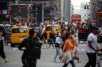 Pedestrians cross a street past traffic in the Midtown neighborhood of New York, US, on Saturday, June 17, 2023.