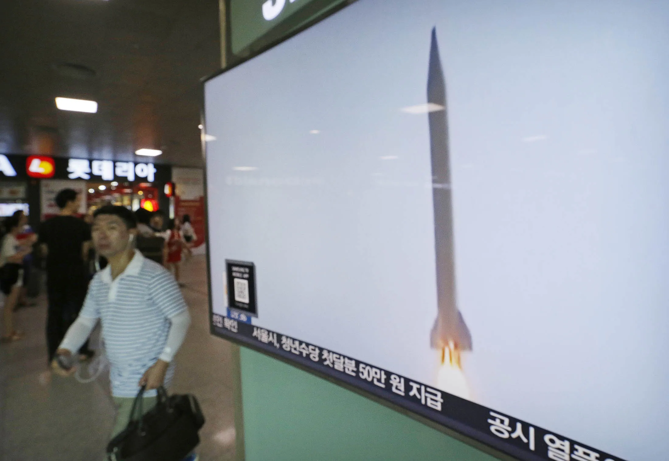 A man passes by a TV news program with file footage of a North Korean rocket launch ono Aug. 3.
