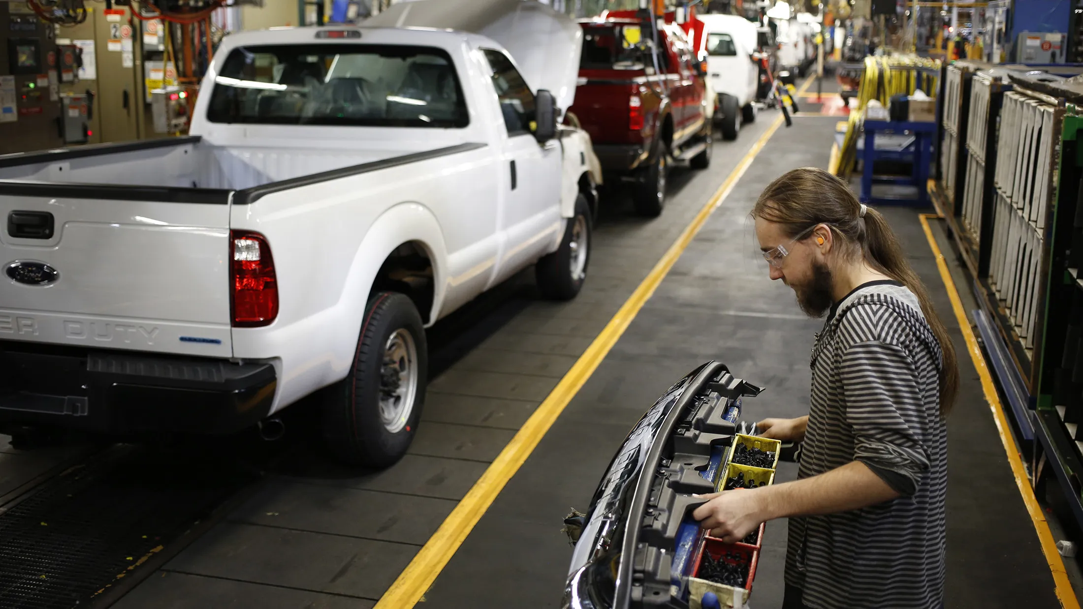 A worker assembles a Ford Motor Co. Super Duty series pickup truck at the company's truck manufacturing plant in Louisville, Kentucky, U.S., on Tuesday, Dec. 1, 2015. Ford said its new four-year contract with the United Auto Workers will increase its U.S. labor costs by less than 1.5 percent annually by letting the company hire more low-cost workers and move production to factories in other countries.
