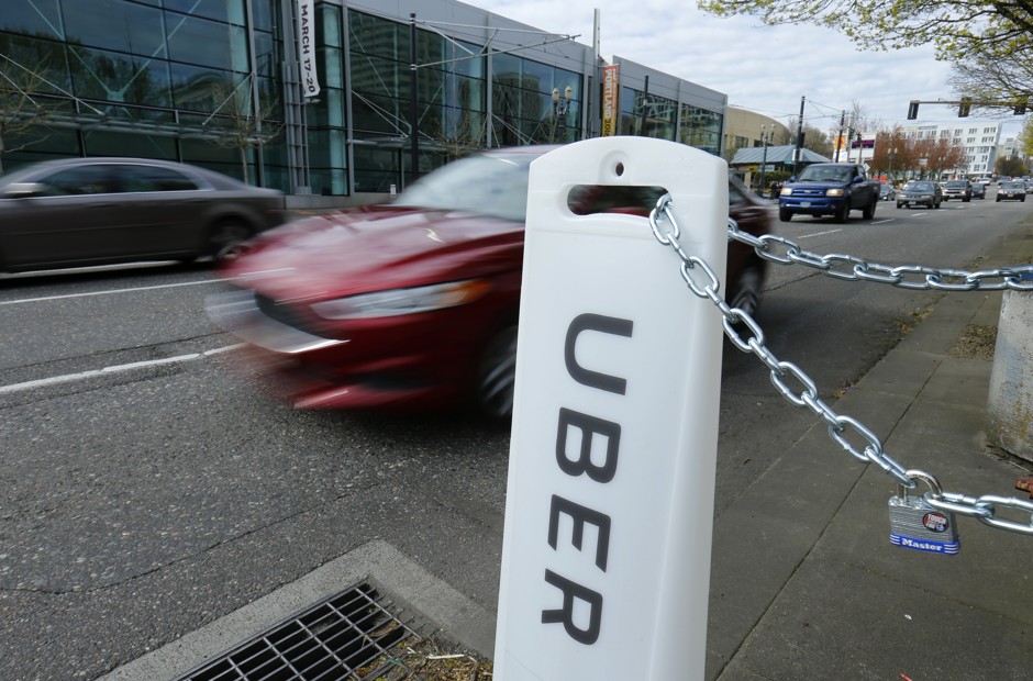An Uber sign points to drop off and pick up location on a city street in Portland, where the company is launching its first electric vehicle program in the U.S.