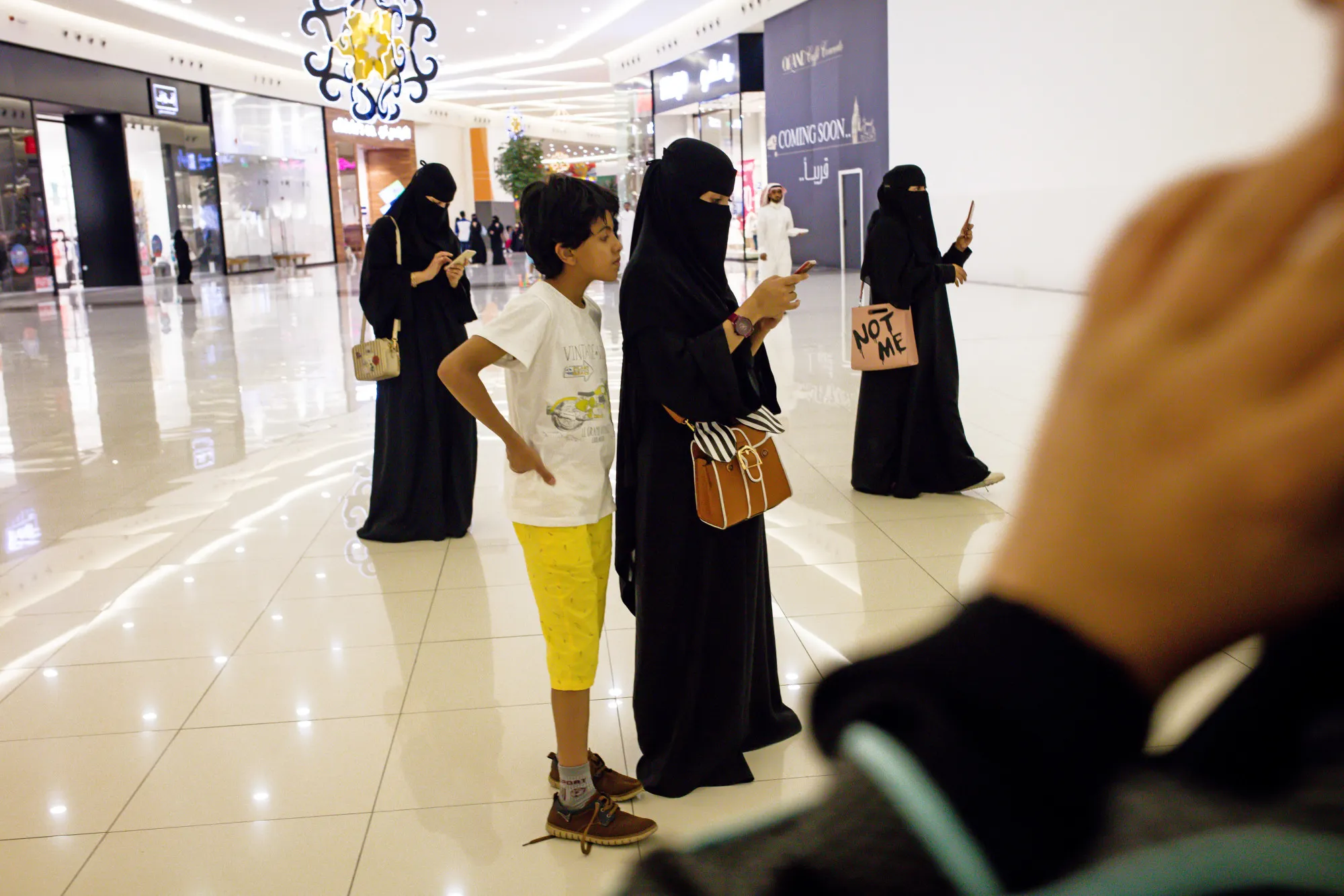 Women use their smartphones while visiting a mall in Jeddah.