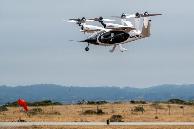 A Joby Aviation pre-production prototype flies over a grassy field in California.