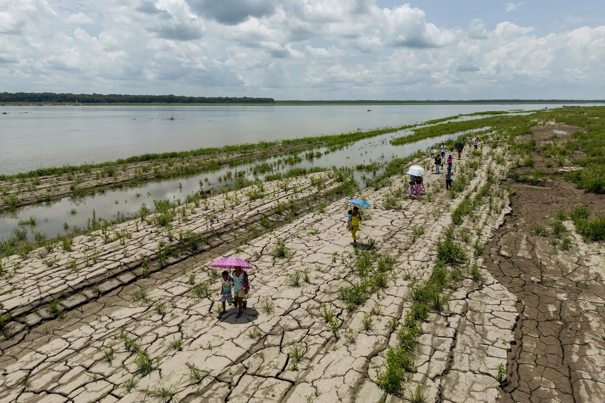 People walk alongside the drought-stricken Amazon River in Santa Sofia, Colombia, in October.