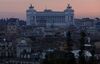 Bronze statues stand atop the Vittorio Emanuele II monument on the skyline at dusk n Rome.