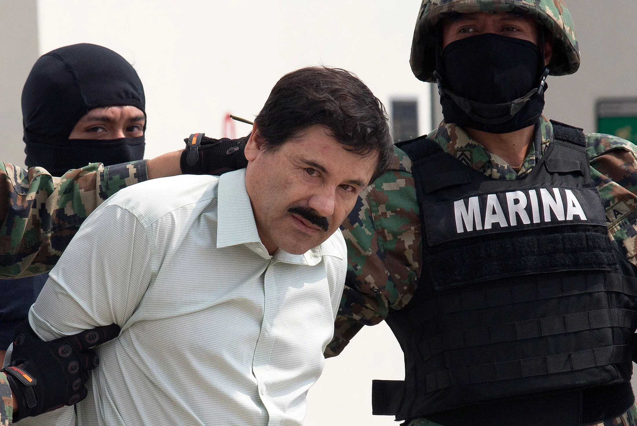 Drug trafficker Joaquin "El Chapo" Guzman is escorted to a helicopter by Mexican security forces at Mexico's International Airport in Mexico city, Mexico, on Saturday, Feb. 22, 2014.
