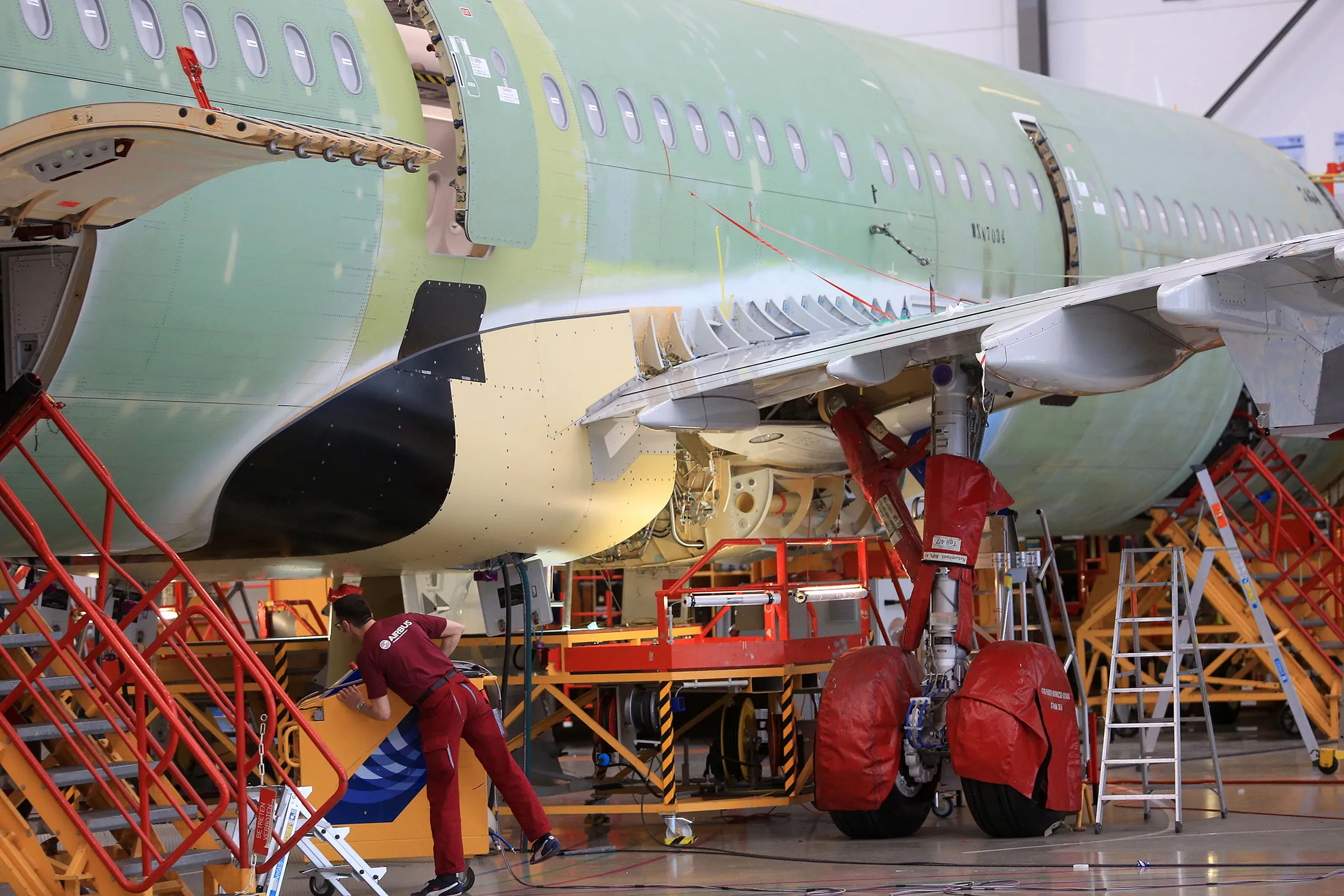 Protective covers sit on the landing gear of an Airbus A320 aircraft on the final assembly line inside the Airbus Group SE factory in Hamburg, Germany, on Friday, Feb. 12, 2016. Deutsche Lufthansa AG, the sole airline so far to take delivery of the new A320neo model, will limit the plane to domestic German routes until glitches with the engine cooling system are resolved in coming weeks.

