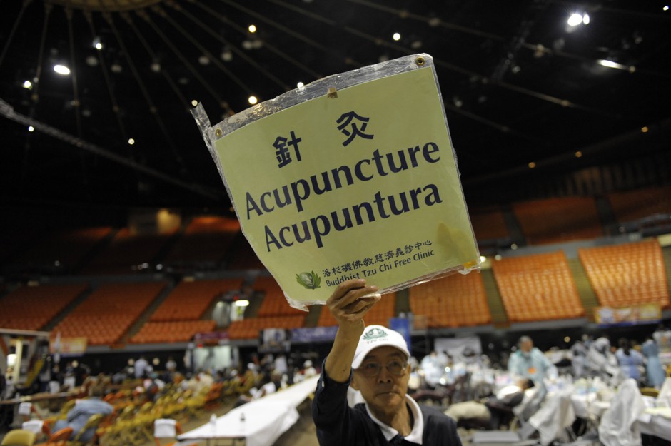 Volunteer Wen Hsien holds up a sign offering free acupuncture on the last day of a free health care clinic set up by Remote Area Medical in Inglewood, California.