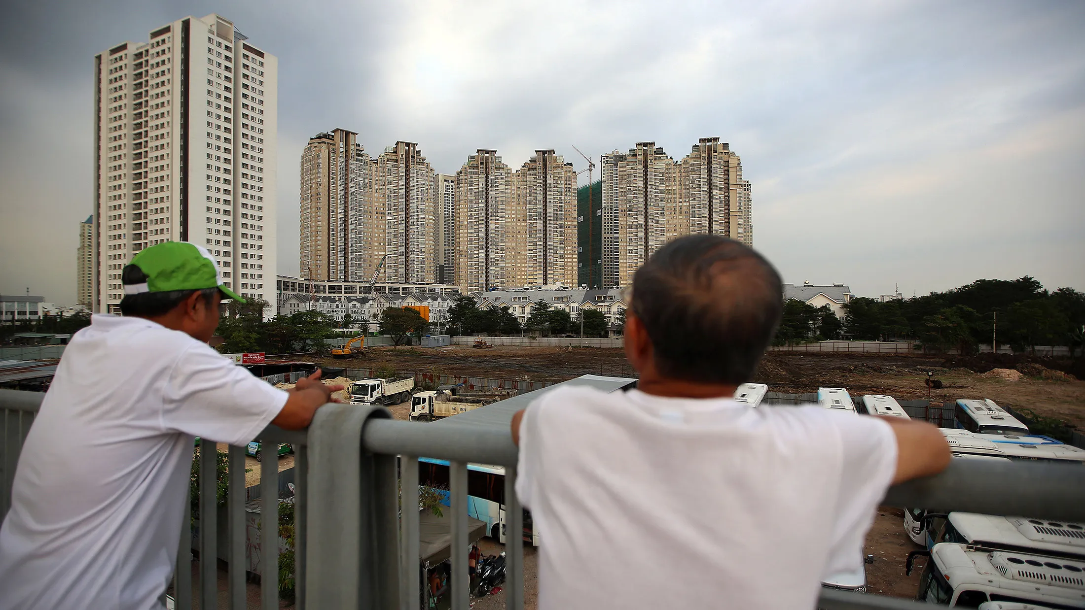Two men look out at residential and commercial buildings in Ho Chi Minh City, Vietnam, on Tuesday, Jan. 10, 2017. Vietnam's economy expanded more than 6 percent for a second year in 2016, defying a regional slowdown to remain one of the world's best performers as retails sales rose 10.2 percent.
