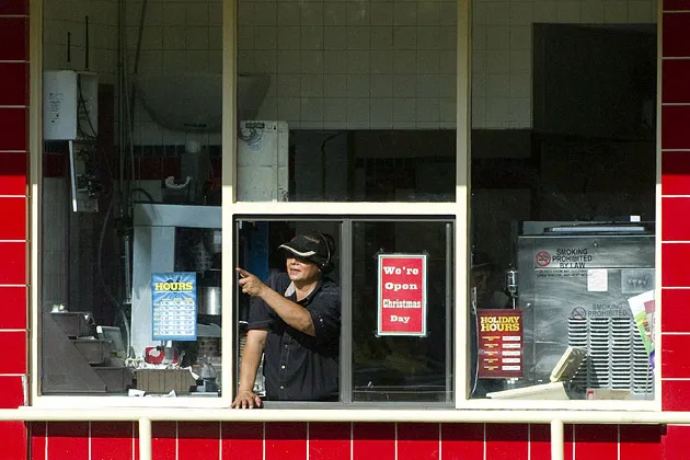A woman working the drive-thru window at a Burger King restaurant points at President Barack Obama's motorcade as it drives past after leaving Marine Corps Base Hawaii at Kaneohe Bay, Hawaii.

