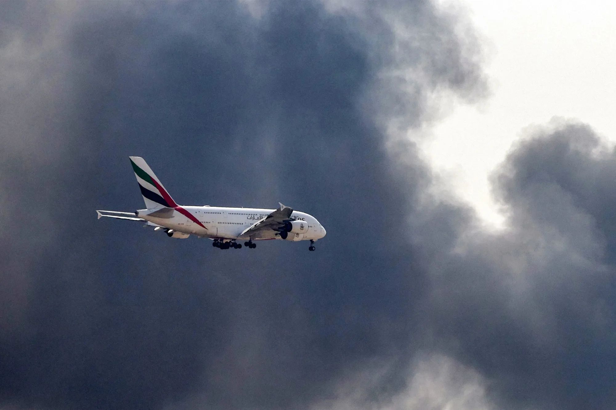 ドバイ空港への着陸態勢にあるエミレーツ航空のエアバスA380が火災による黒煙を横切る様子（3月16日）
