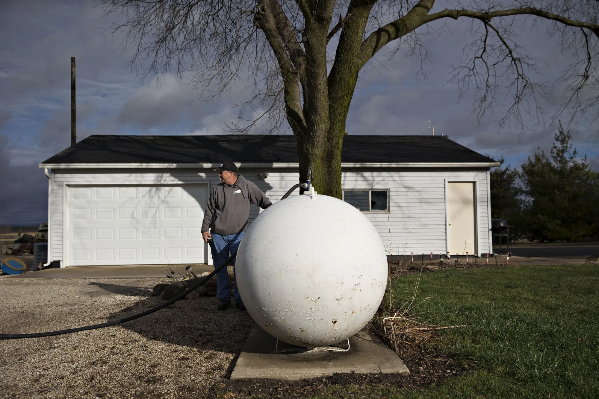 A worker fills a tank with liquid propane gas during delivery at a home in Wyanet, Illinois.