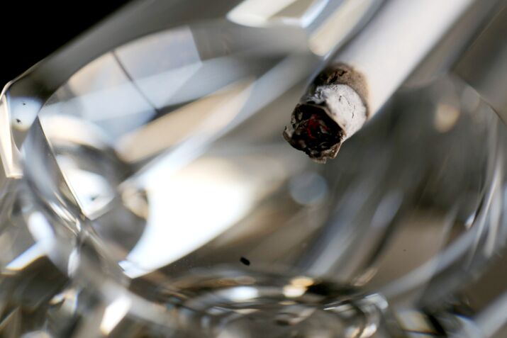 A cigarette sits in an ashtray