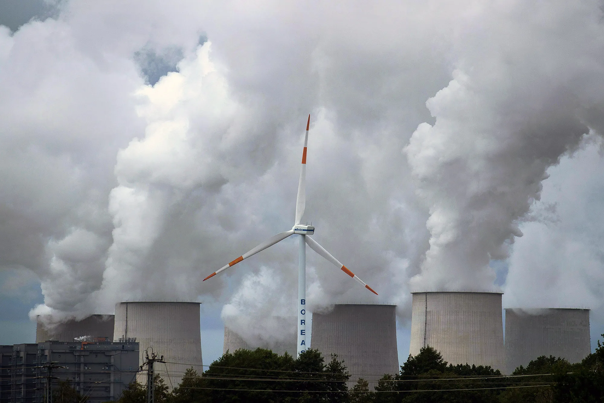 A wind turbine operates near emissions rising from a power plant&nbsp;in Barenbrueck, Germany.&nbsp;