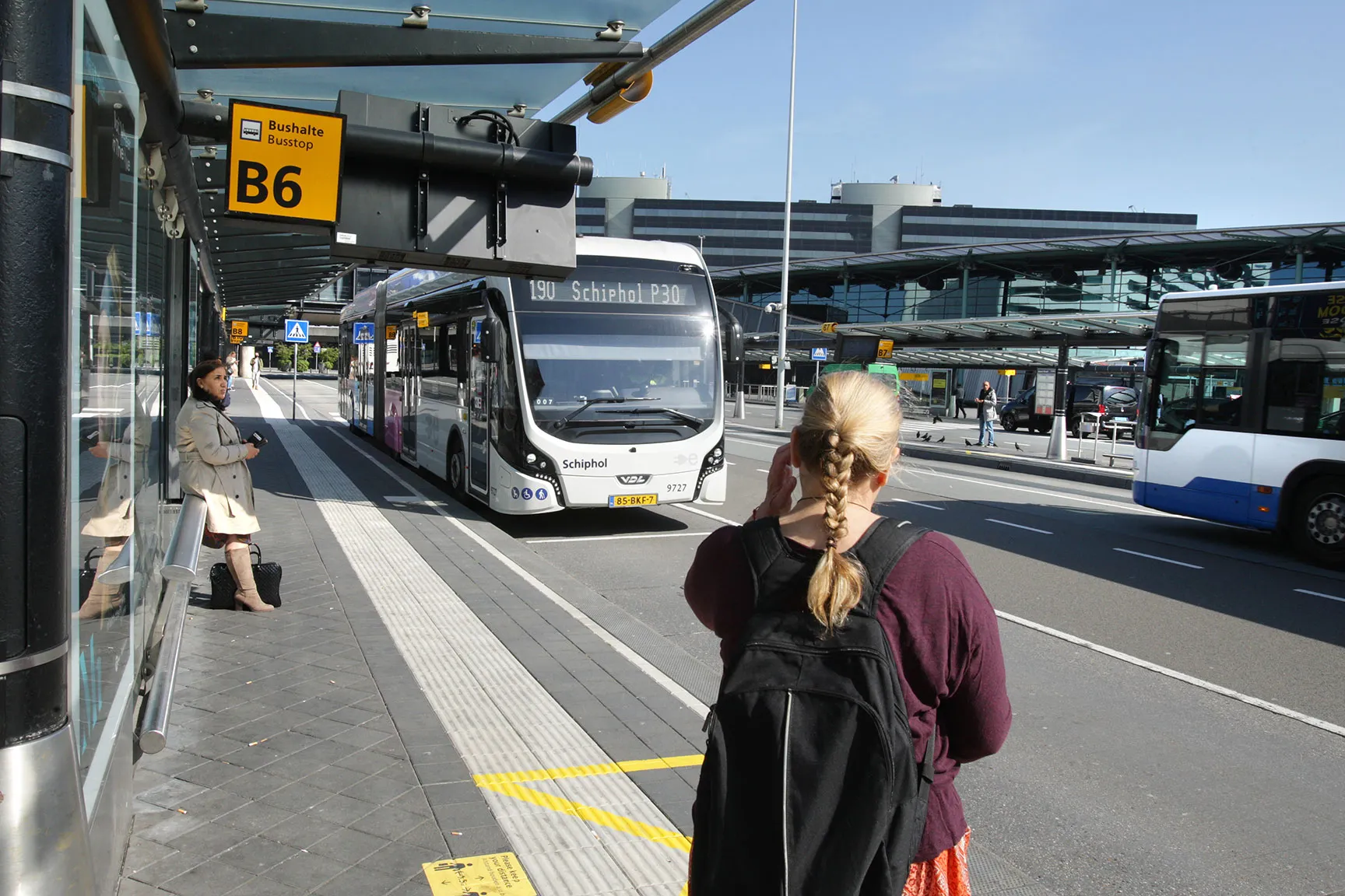 Travelers wait at a bus stop at the Schiphol Airport&nbsp;in Amsterdam, Netherlands on May 26.