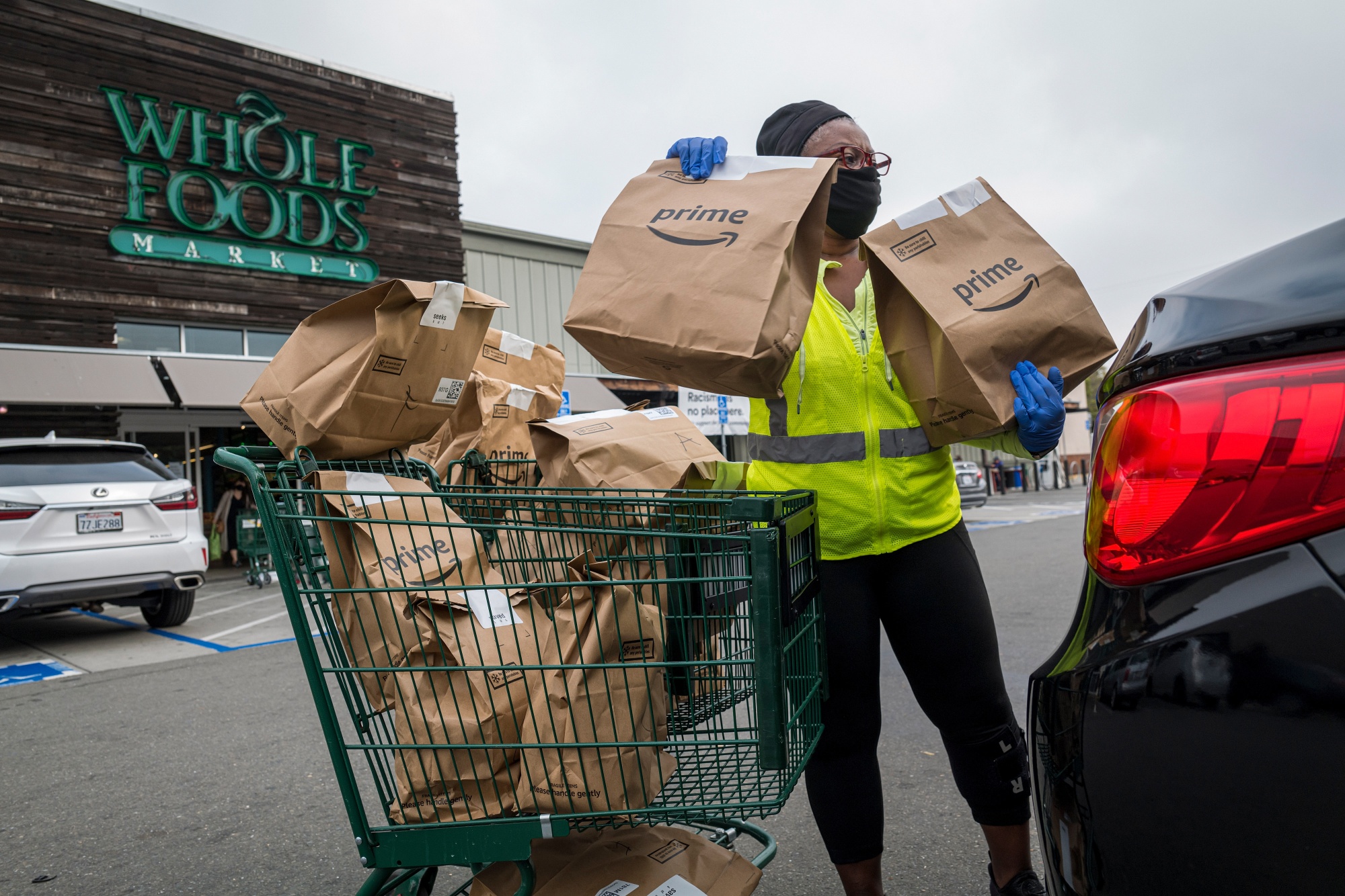 An independent contractor loads Amazon Prime grocery bags into a car outside a Whole Foods Market in Berkeley, California.