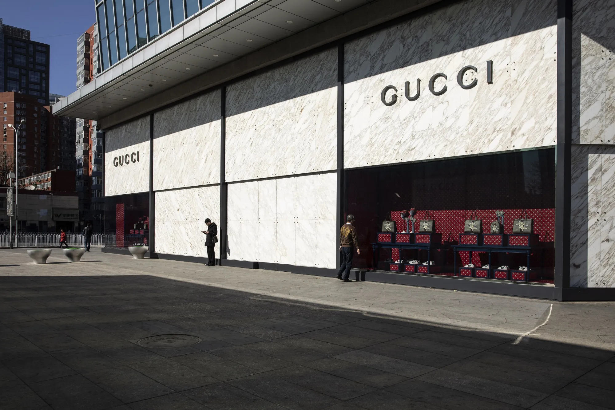 Pedestrians stand outside a Gucci store in Beijing.