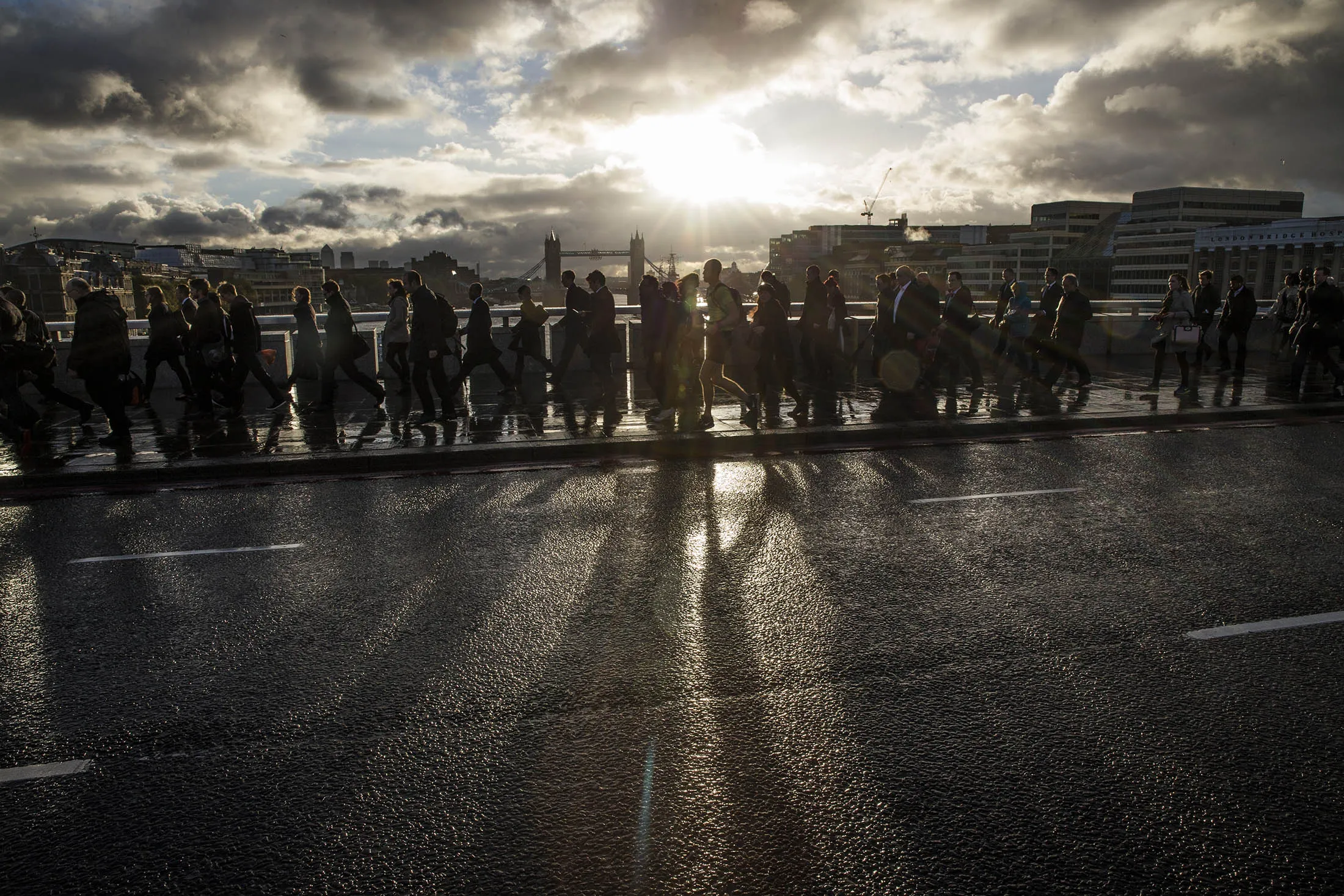 LONDON, ENGLAND - OCTOBER 21: City workers walk over London Bridge as the early morning sun breaks through clouds on October 21, 2014 in London, England. Despite weather warnings issued by the Met Office for high winds and rain off the back of Hurricane Gonzalo, those predictions didn't materialise in London.
