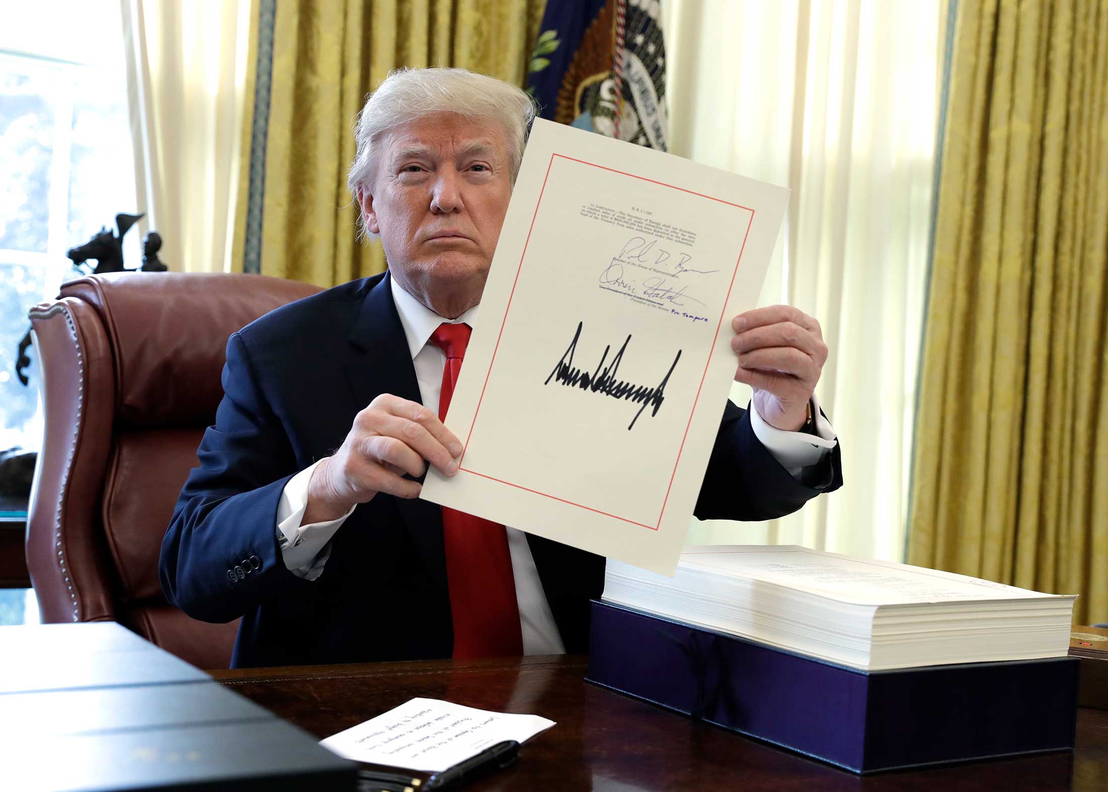President Trump shows his signature on a $1.5 trillion tax overhaul package in the Oval Office of the White House on Dec. 22, 2017.&nbsp;