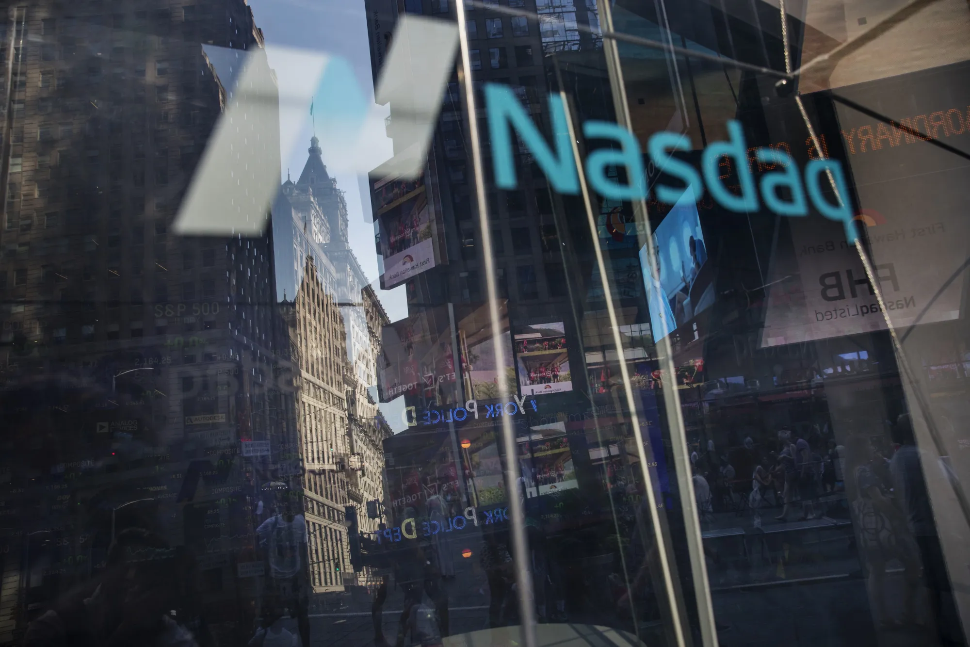 Pedestrians are reflected in the window of the Nasdaq MarketSite in New York.