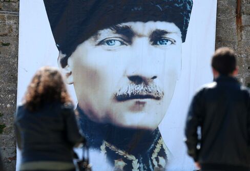 People walk past a portrait of Kemal Ataturk.
