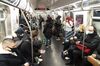 Commuters in a full subway. All seats are taken.