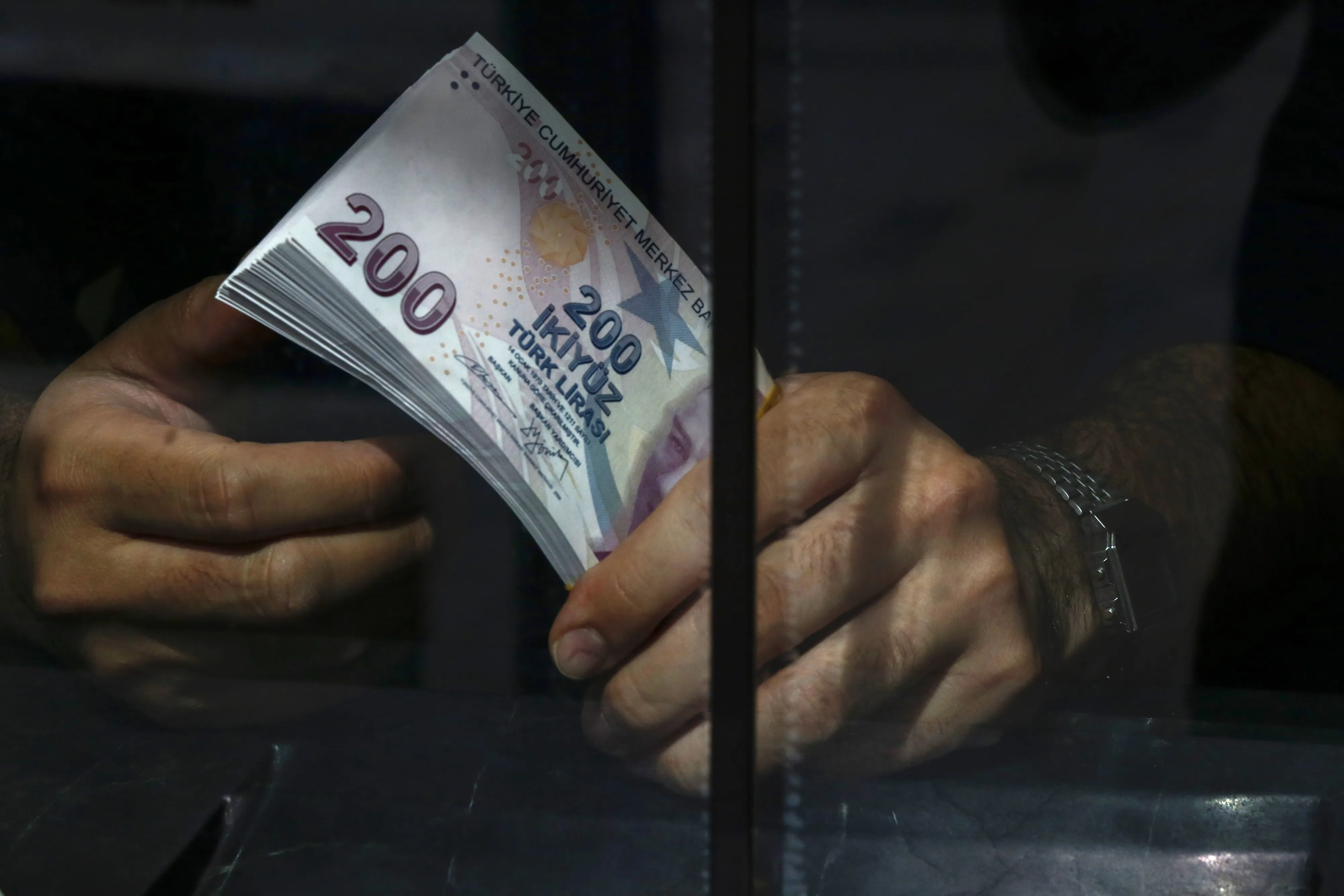 An emloyee holds a wad of 200 Turkish lira banknotes in a currency exchange in Istanbul, Turkey.