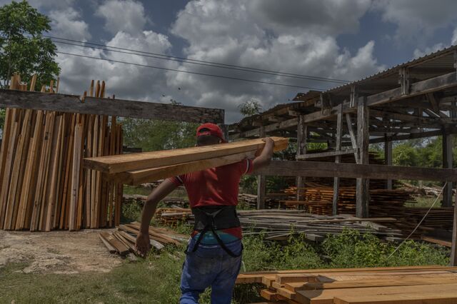 A sawmill worker carries planks of wood in Petcacab.