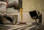 A worker places personal jewelry into a furnace to convert it into a gold bar at a verification center in India.