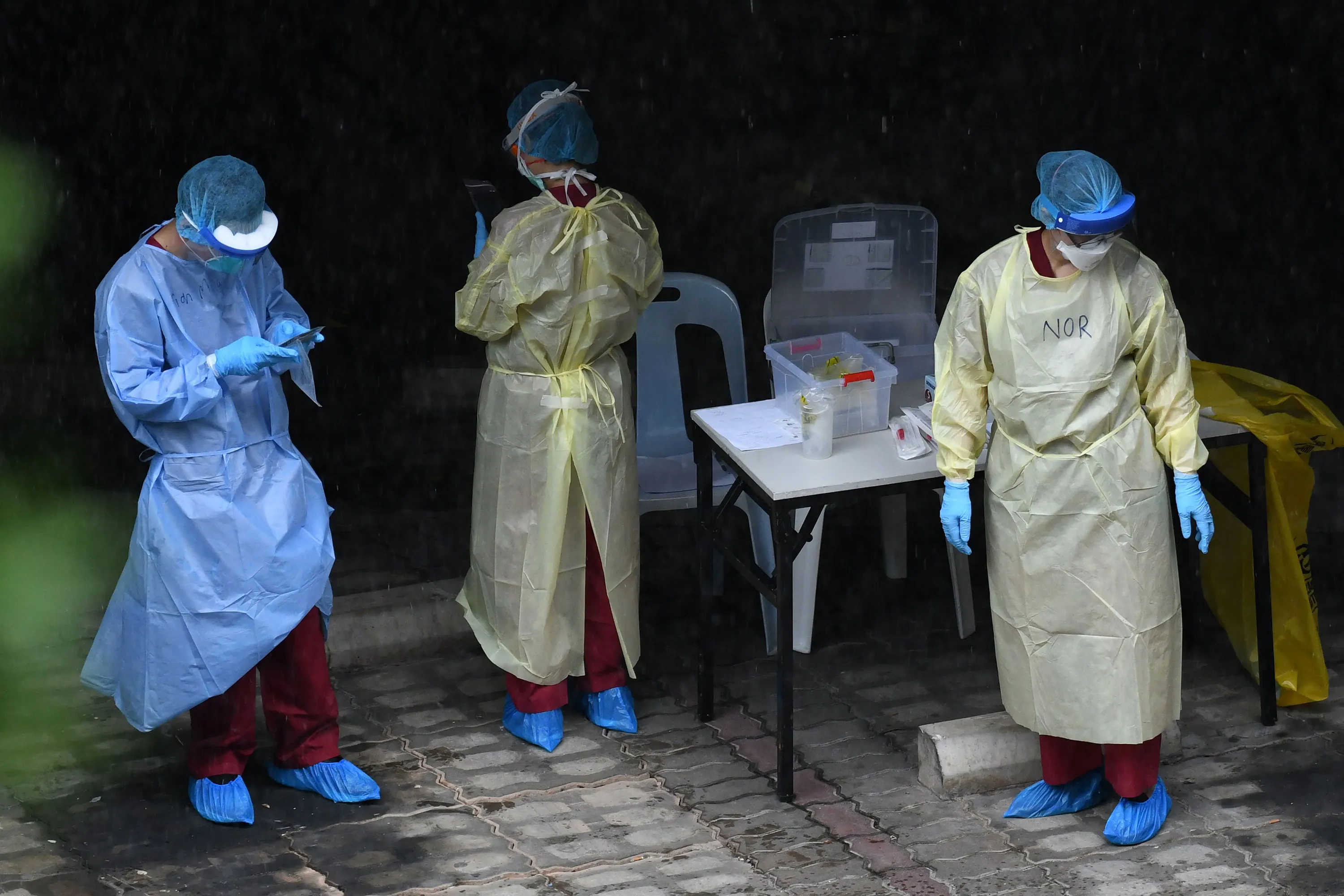 Healthcare workers dressed in personal protective equipment prepare to test migrant workers for the Covid-19 at a foreign workers' domitory in Singapore on April 27.