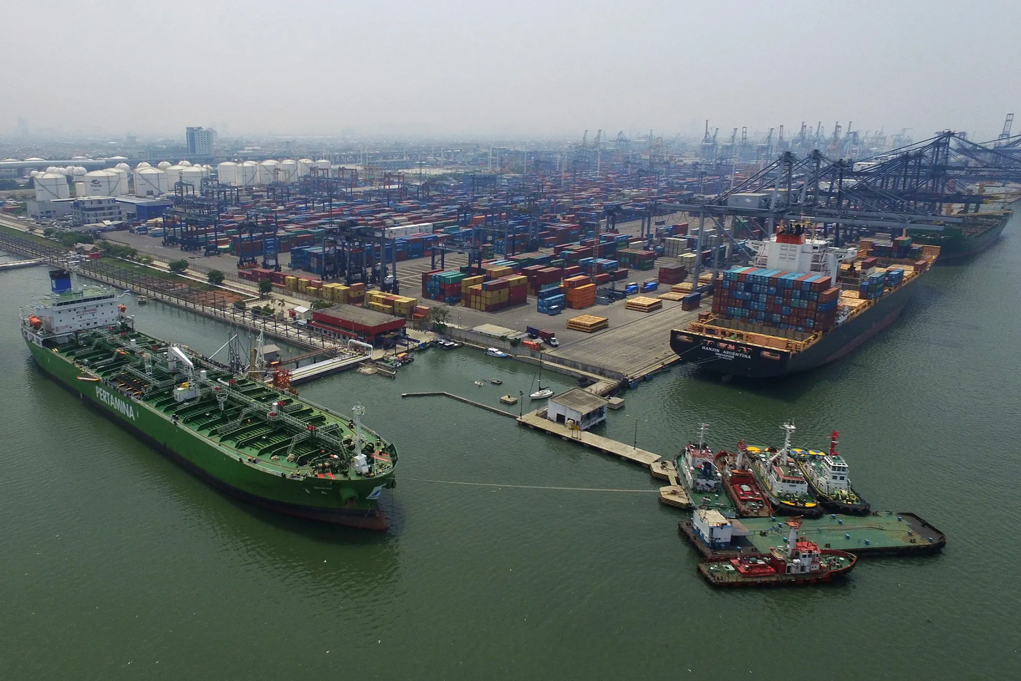 An oil tanker, left, sits docked at a PT Pertamina facility at Tanjung Priok Port in this aerial photograph taken in Jakarta, Indonesia, Nov. 30, 2015.
