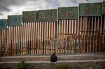 A person sits in front of a section of the U.S.-Mexico border wall in Tijuana, Mexico, on Saturday, May 19, 2018.