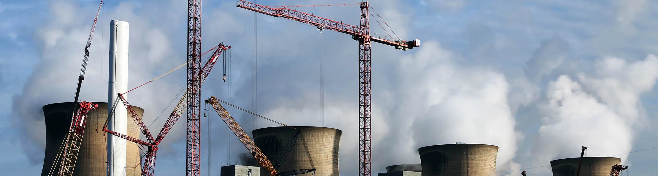 Construction cranes stand on the site of a new multi-fuel plant as cooling towers emit vapor at Ferrybridge coal fired power station, in Ferrybridge, U.K., on Tuesday Nov. 26, 2013. SSE Plc, the U.K.'s second-biggest energy supplier, pledged to curb increases in customer bills if the government cuts environmental levies that push up tariffs.
