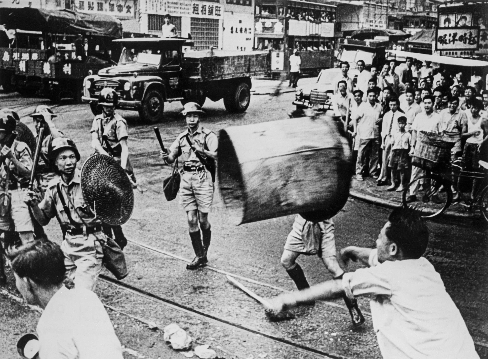A protester launches a trash can at riot police in the streets of Hong Kong in 1967.