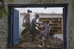 People salvage usable items from their house, after the roof collapsed due to heavy rains, in Peshawar, Pakistan, Thursday, July 28, 2022. The National Disaster Management Authority said Wednesday that 337 people died across the country in rain-related incidents. (AP Photo/Muhammad Sajjad)