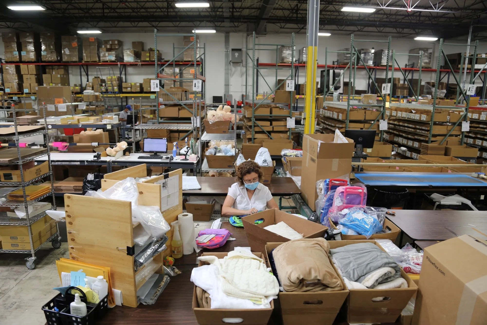 An employee wearing a protective mask works at the Gifts For You company warehouse.