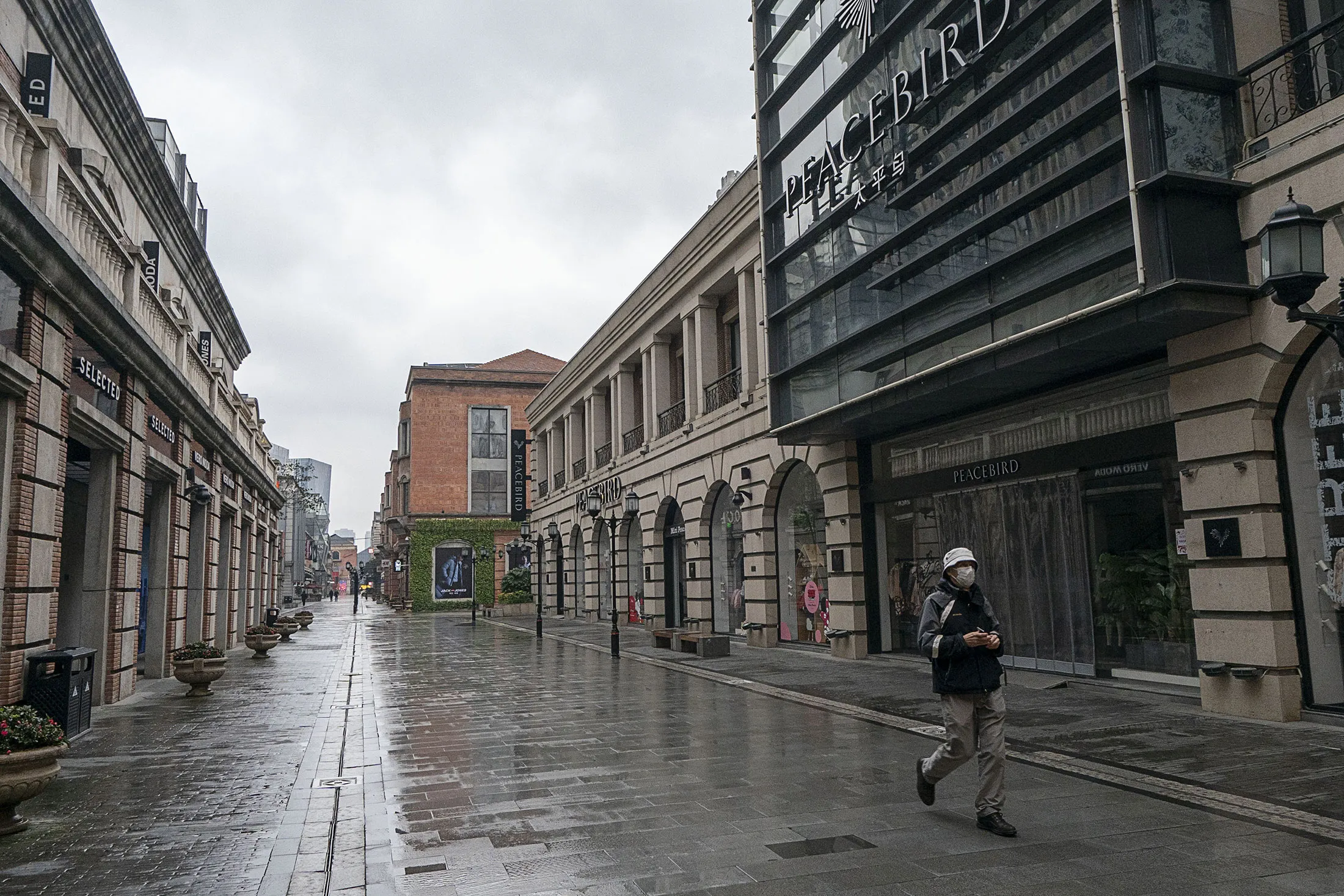 A man wearing a mask walks past a commercial area in Wuhan, China, on Jan. 26.