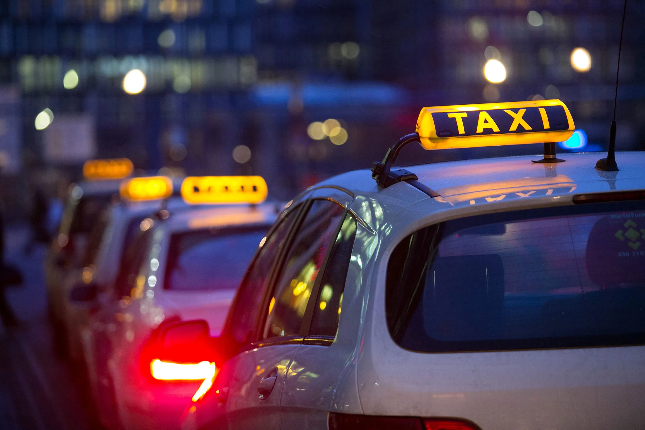 Rooftop hire signs sit illuminated on taxis at a taxi rank outside Berlin Central railway station, in Berlin, Germany.
