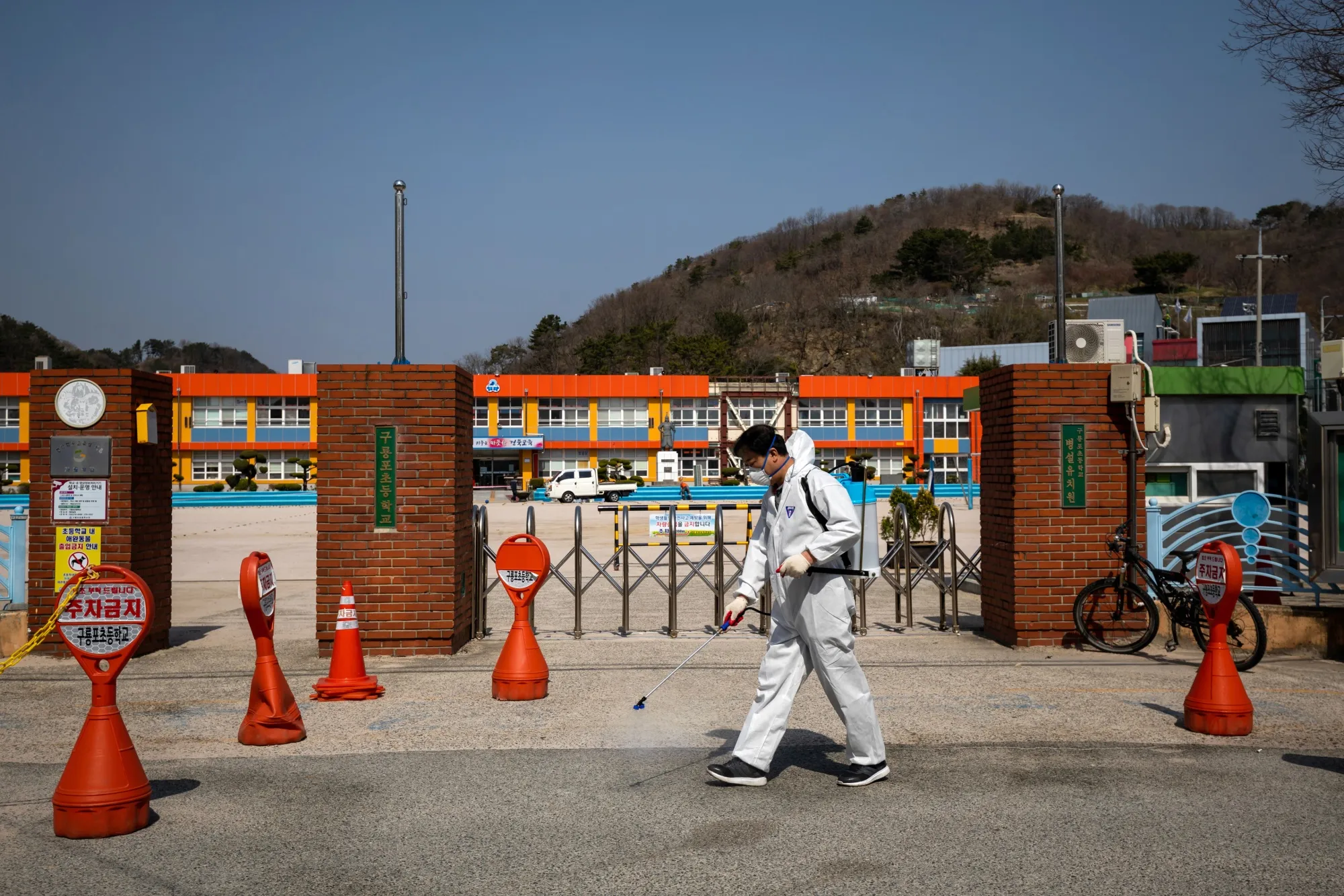 A volunteer sprays disinfectant outside an elementary school in Pohang, South Korea, on&nbsp;March 21.