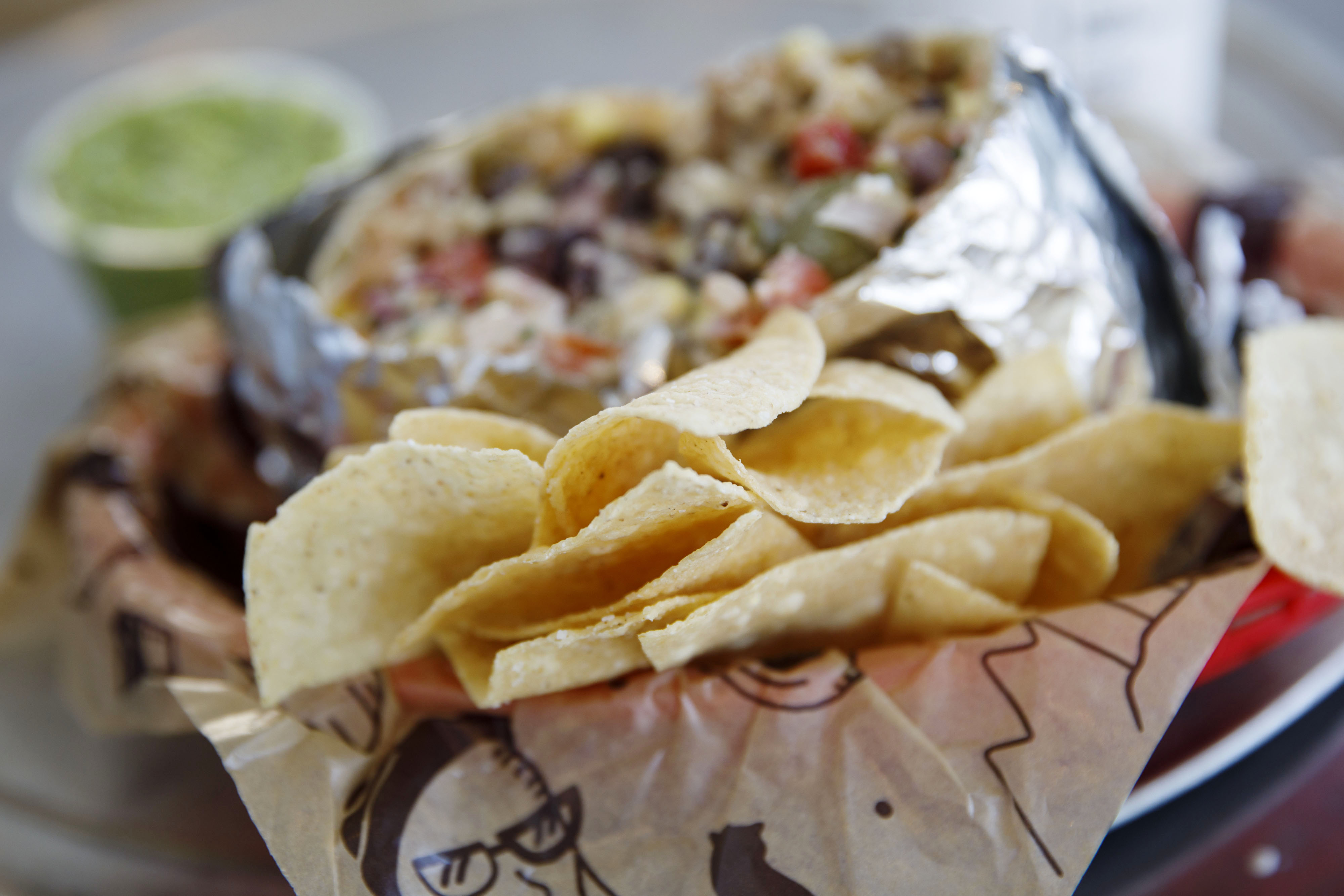 Tortilla chips, a chicken burrito, and a cup of guacamole are arranged for a photograph at a Chipotle Mexican Grill Inc. restaurant.