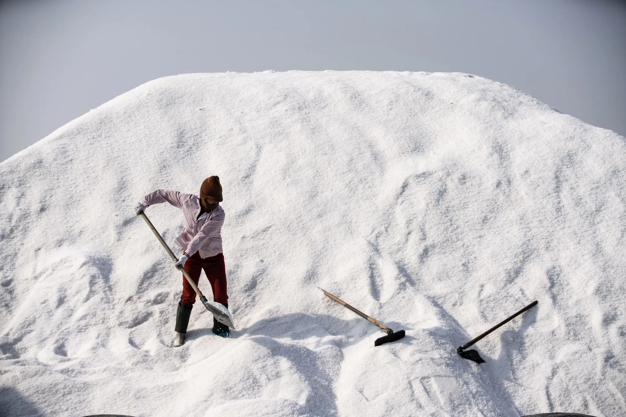 A worker shovels salt at a salt field in Putian, China.