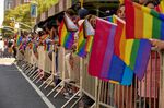Spectators hold Pride flags during a Pride March.