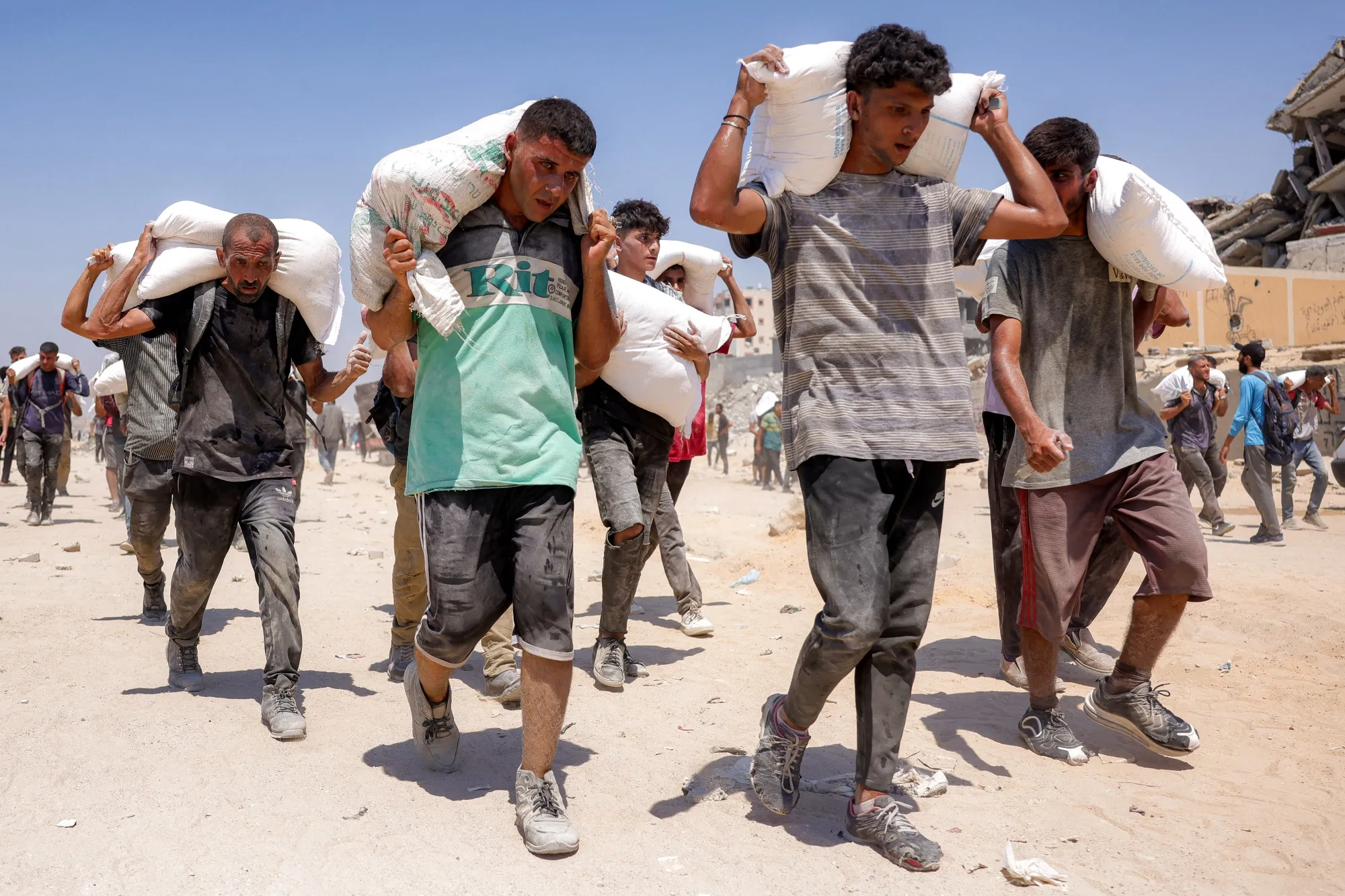 People walk with sacks of flour delivered after trucks carrying humanitarian aid entered northern Gaza on July 27.