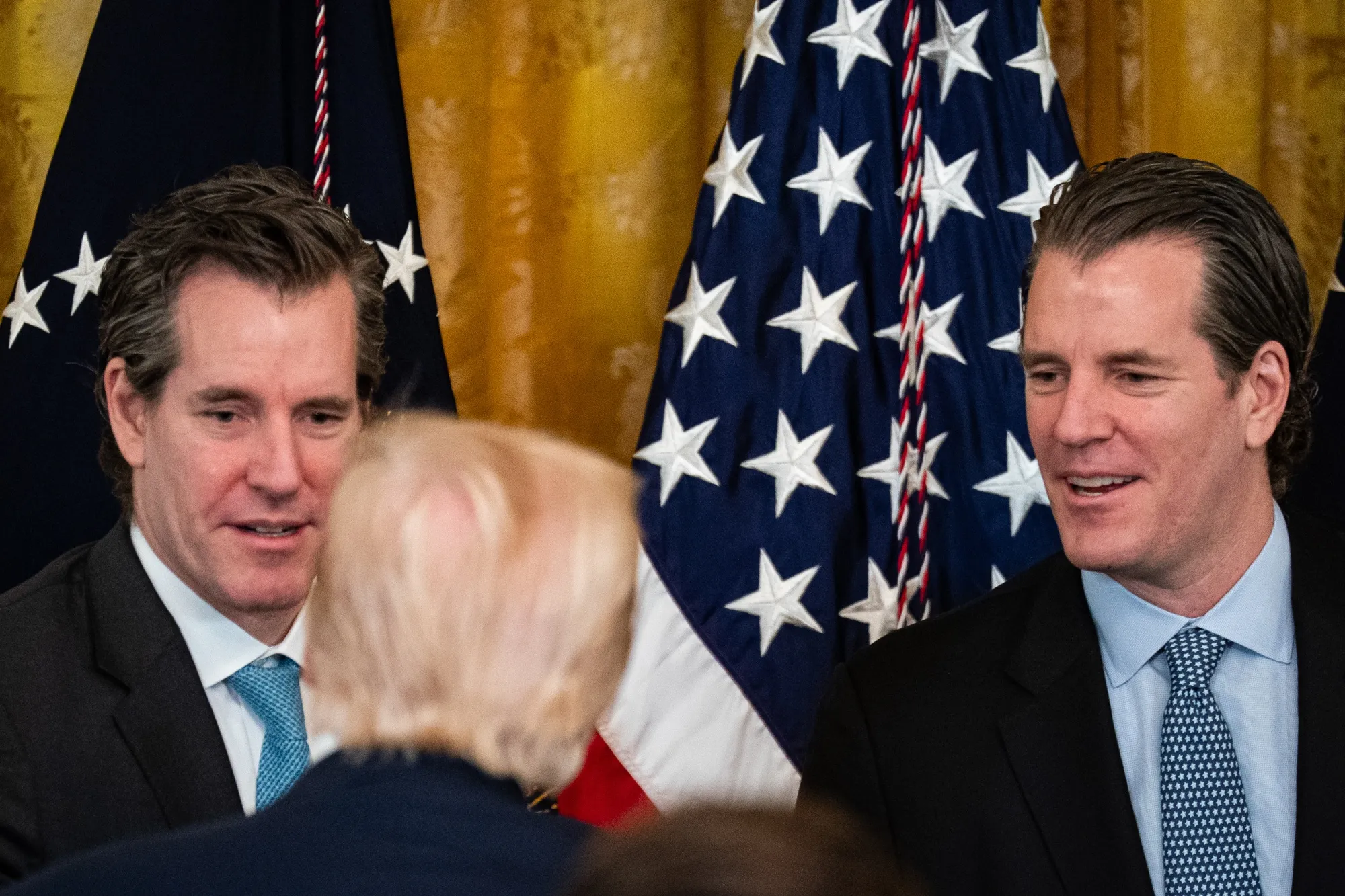 Cameron Winklevoss, left, and Tyler Winklevoss speak with President Trump during a signing ceremony for the GENIUS Act on July 18.