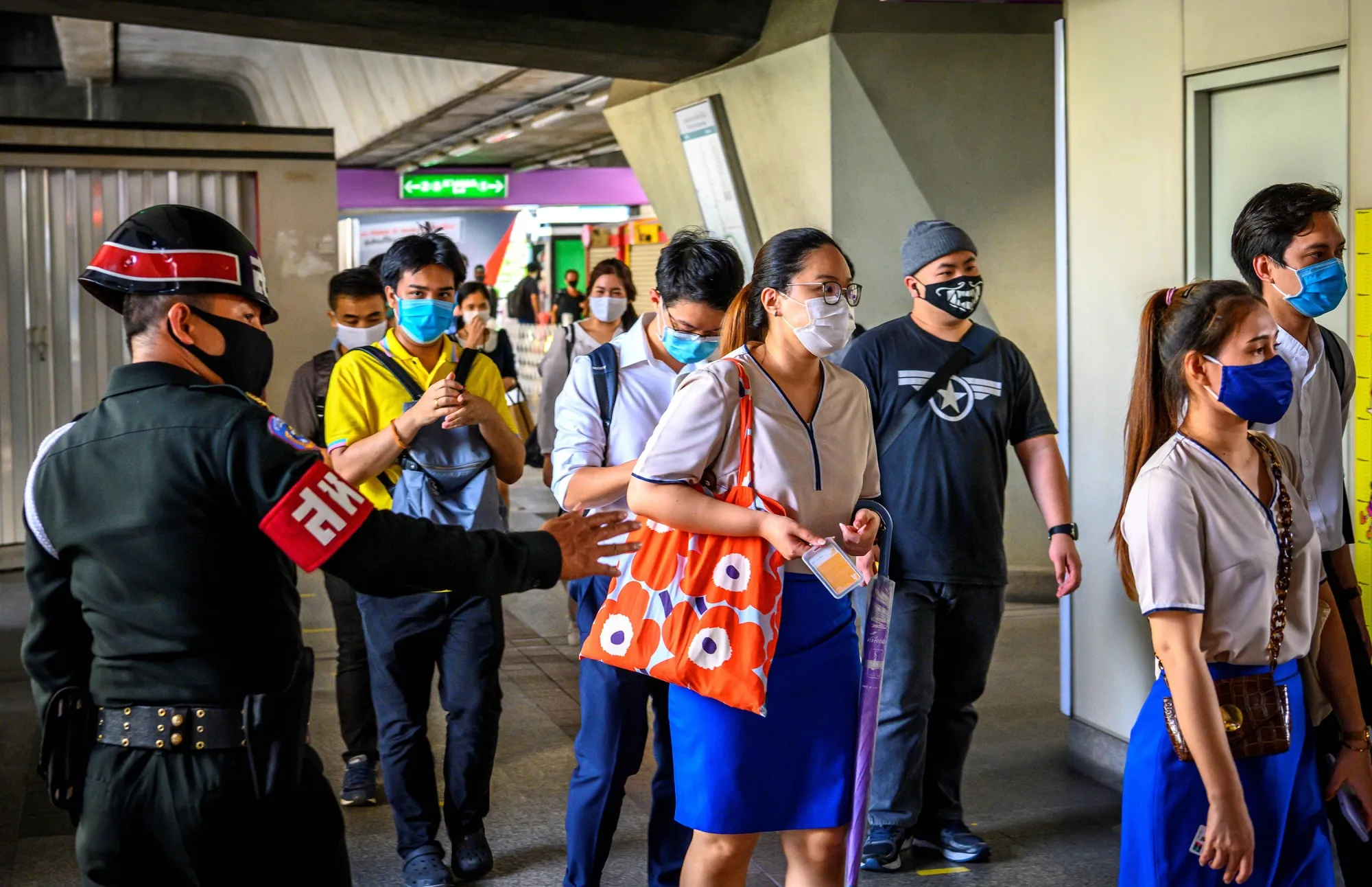A security officer enforces social distancing rules at a commuter train station at rush hour in Bangkok on May 25.