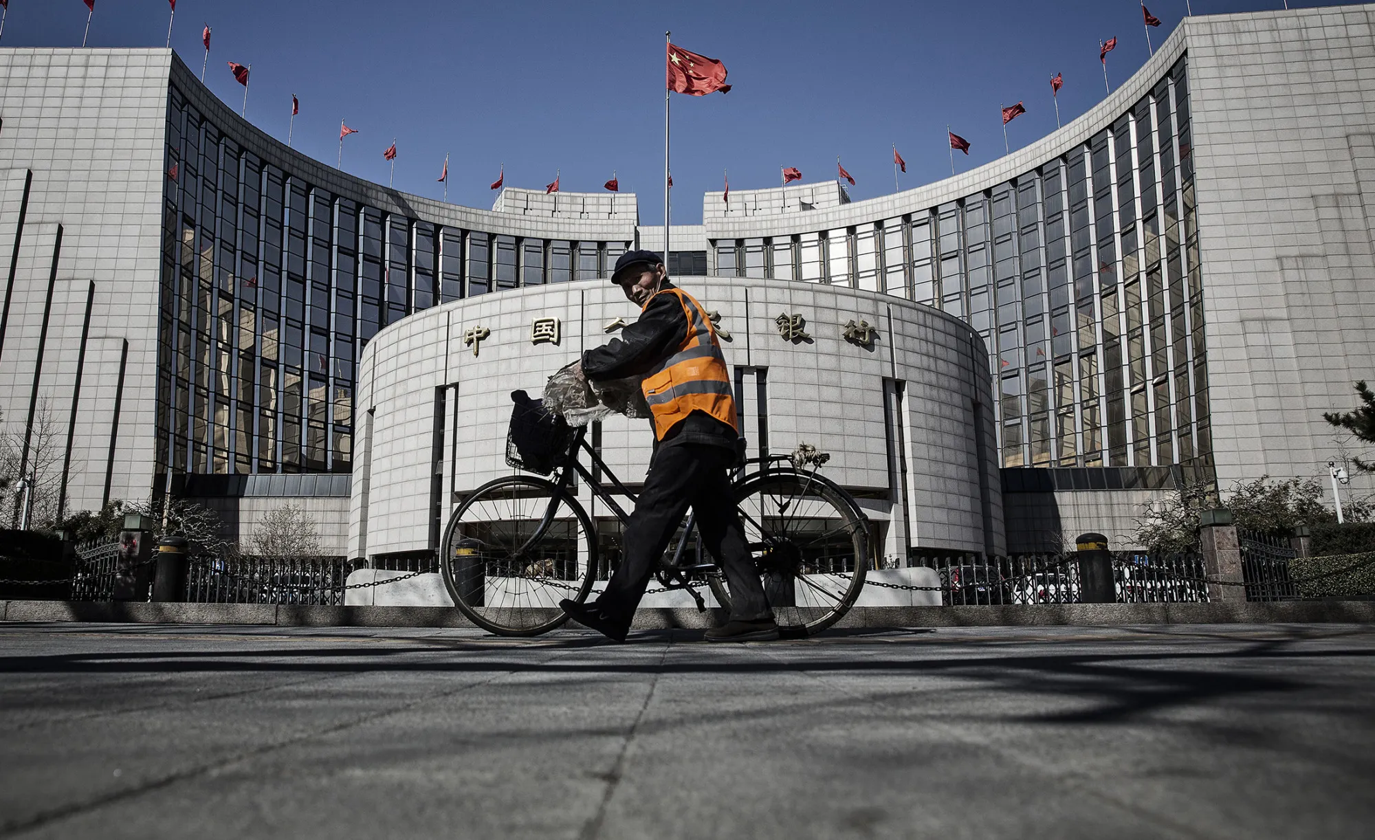 A man pushes a bicycle past the People's Bank of China (PBOC) headquarters in Beijing.

